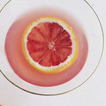 blood orange martini garnished with orange slice.