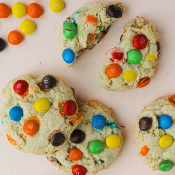 chewy M&M sugar cookies on pink background.