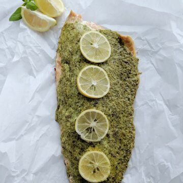 herb and cheese crusted salmon with lemon slices.