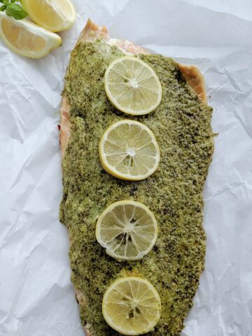 herb and cheese crusted salmon with lemon slices.