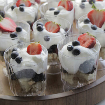 individual trifle cups topped with whipped cream and berries.