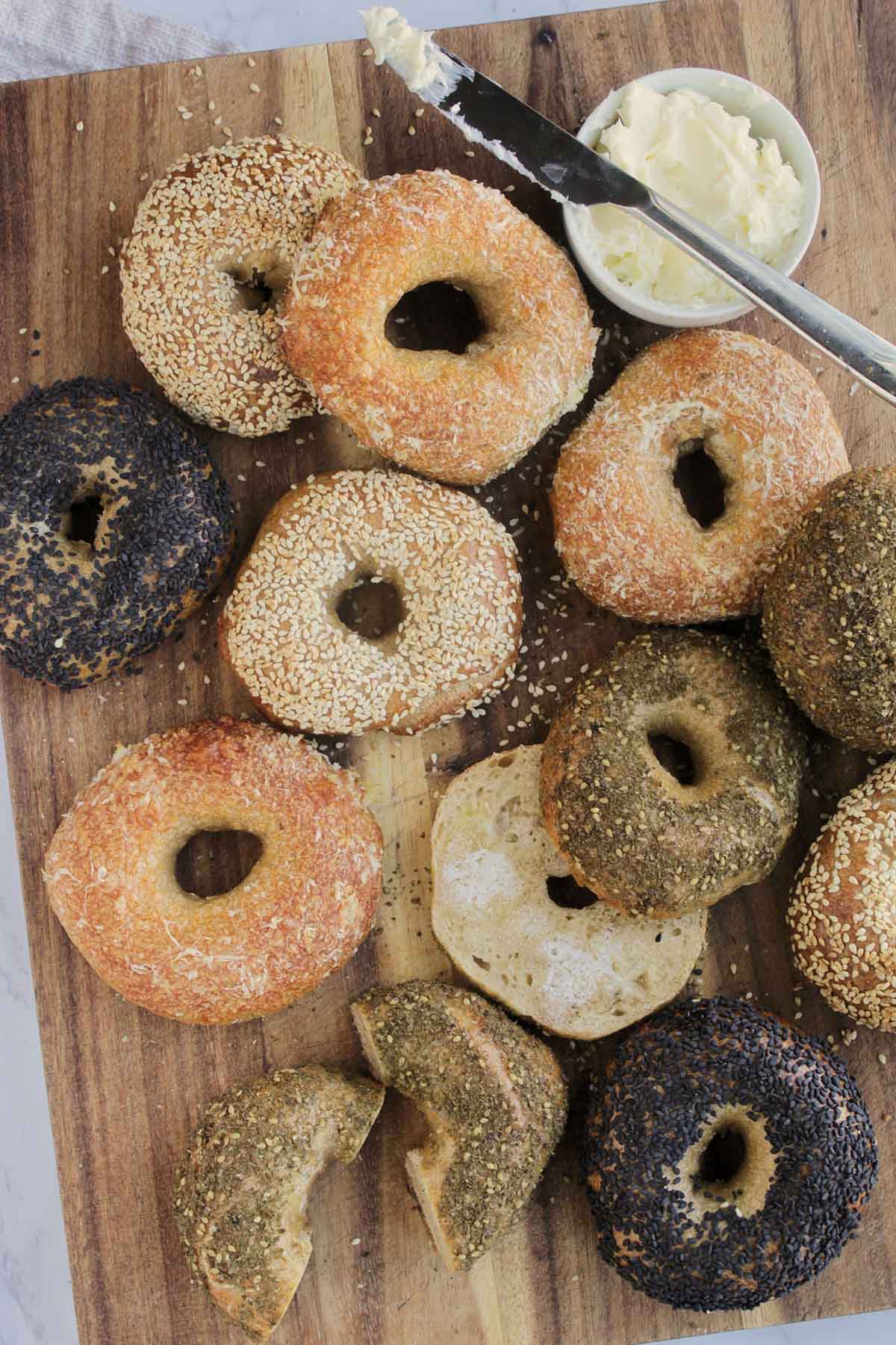 various flavored sourdough bagels on wooden cutting board.