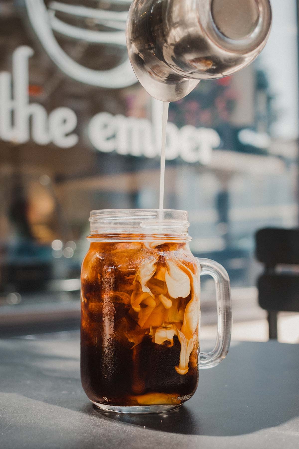 pouring cream into cold brew coffee.