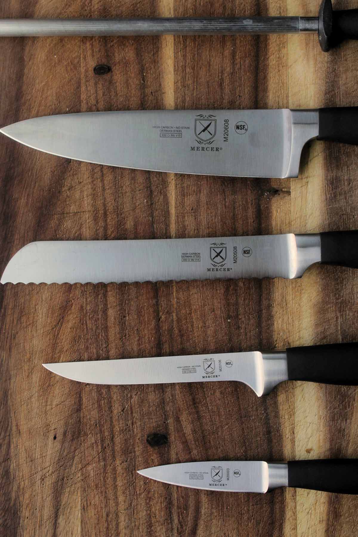 various types of Mercer Culinary knives on cutting board.
