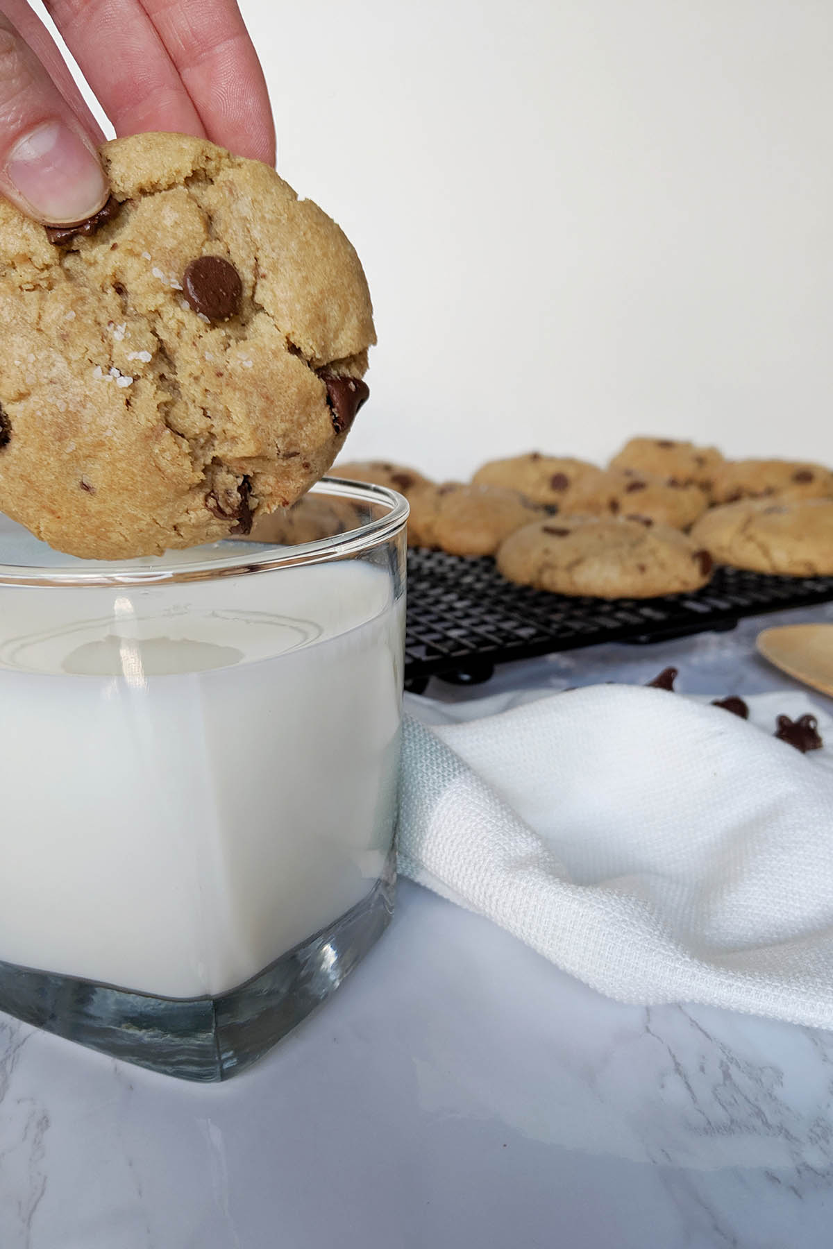 dunking chocolate chip cookie into a glass of milk.