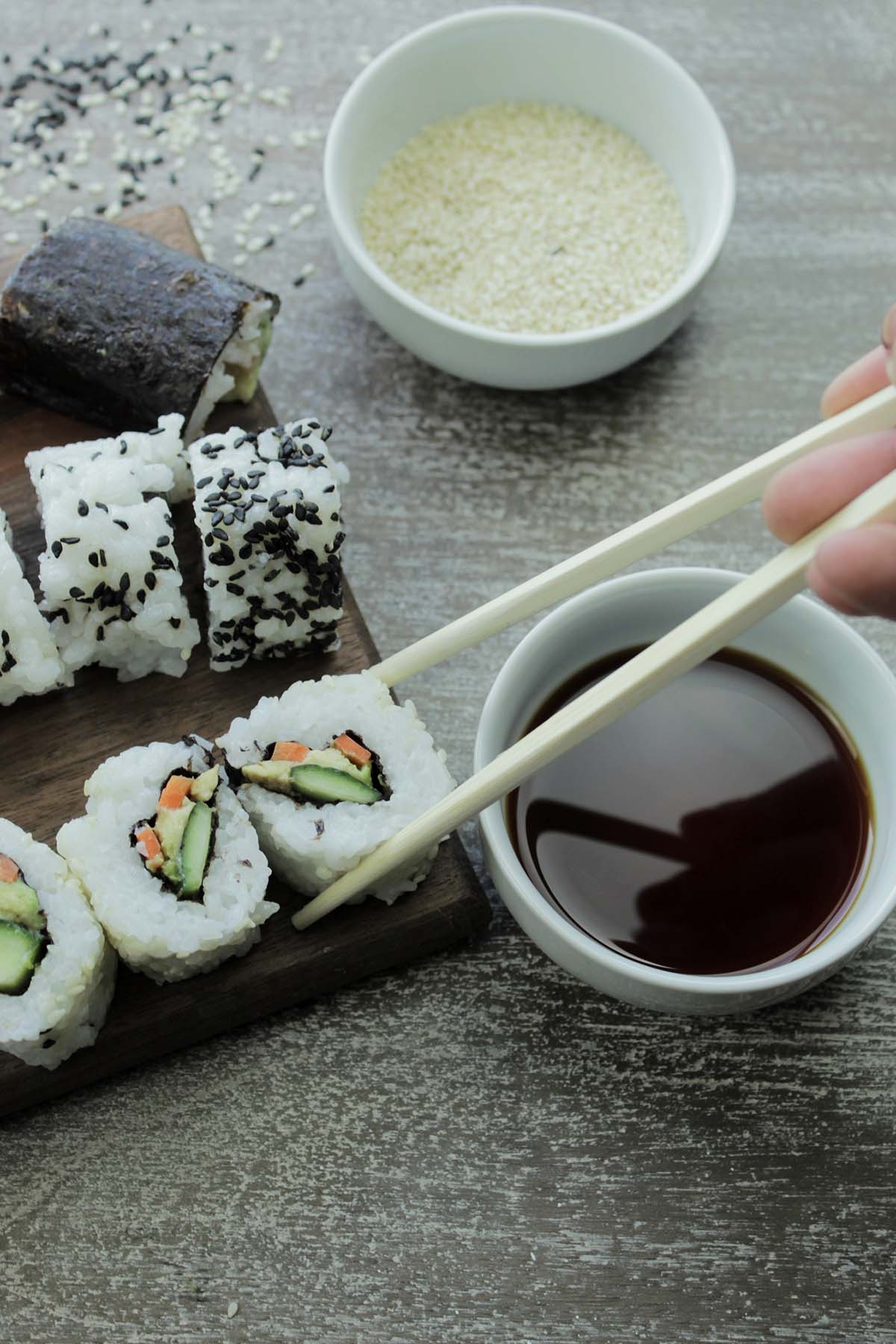 holding a piece of sushi with chopsticks.