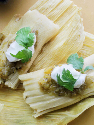 two cooked tamales laying on corn husks.