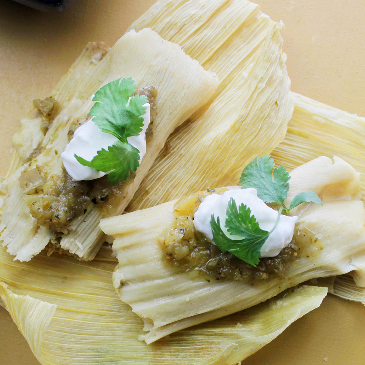 two cooked tamales laying on corn husks.