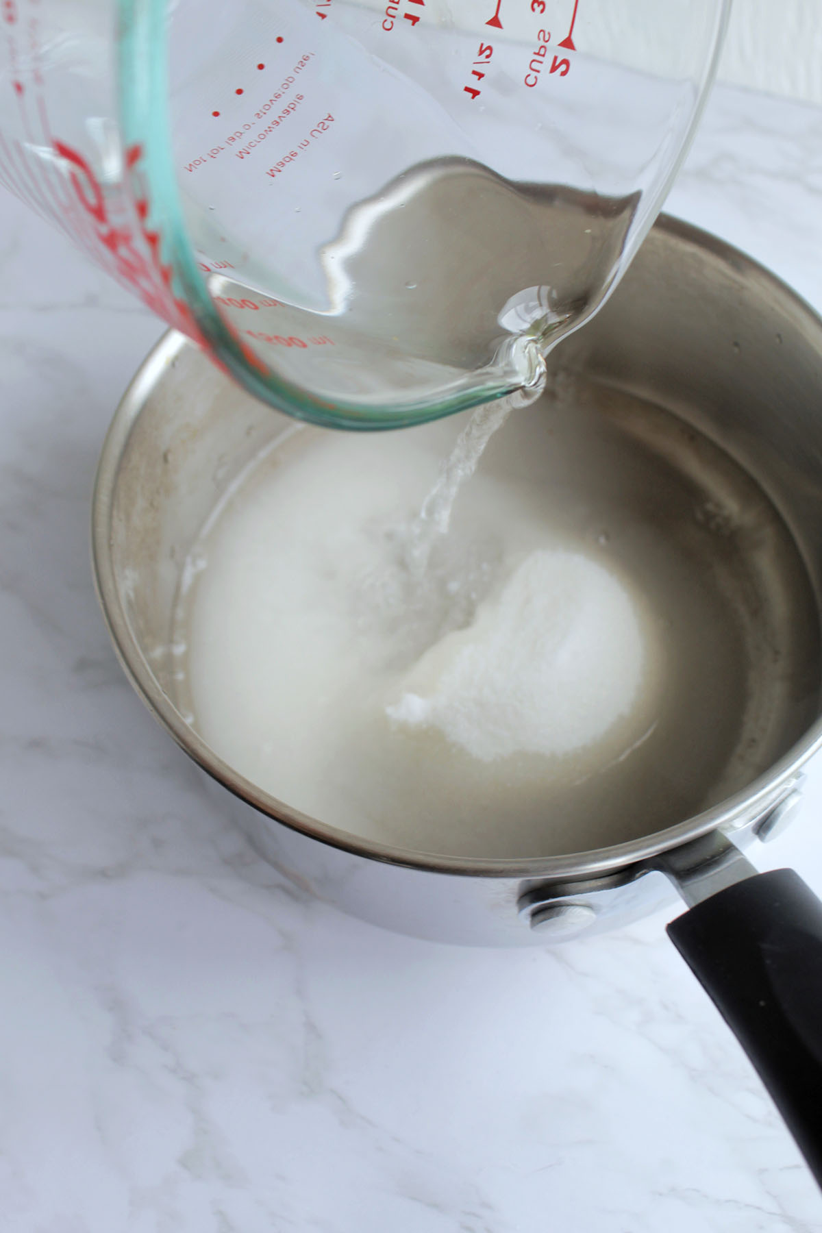 pouring water into a saucepan of sugar.