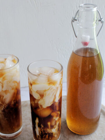 jar of vanilla syrup next to glasses of cold brew.