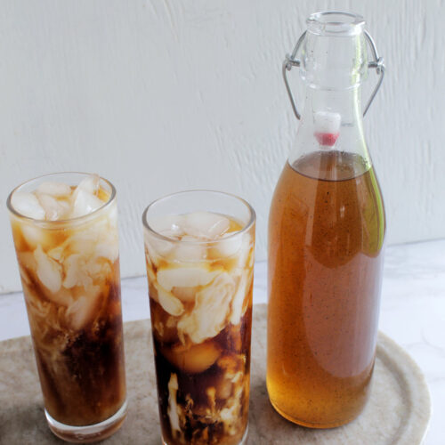 jar of vanilla syrup next to glasses of cold brew.