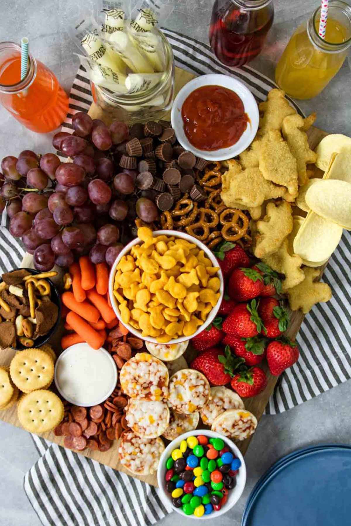 snack board filled with crackers, candy, fruit, and mini snacks.