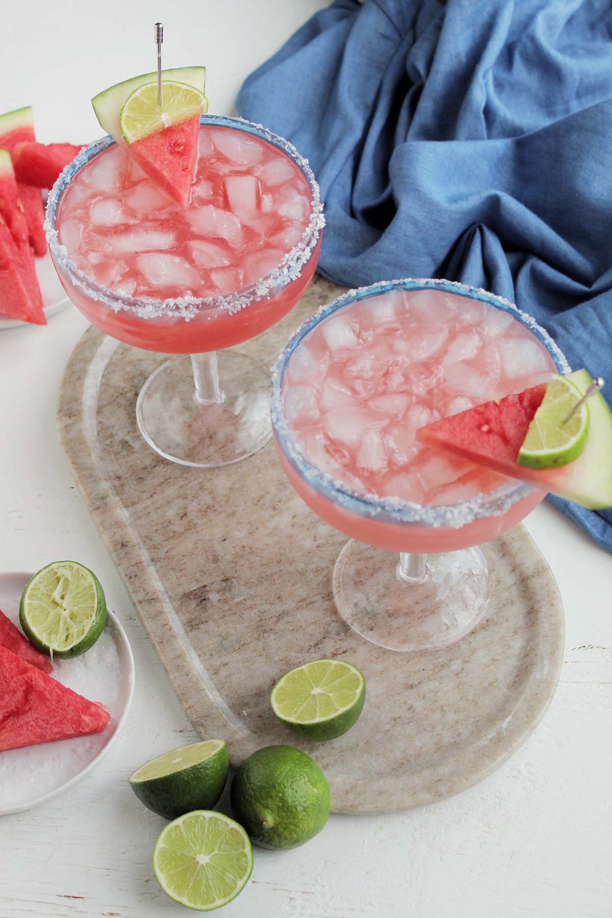 two watermelon margaritas in a salted coupe glass with a watermelon garnish.