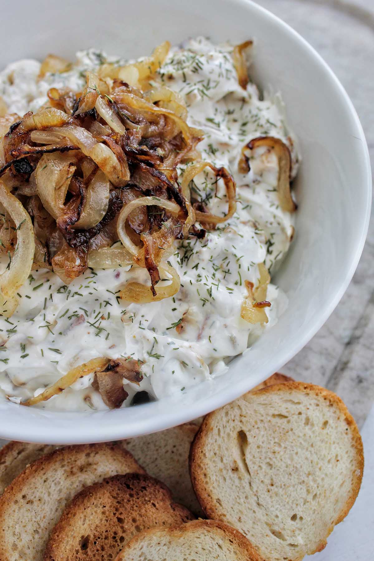 serving bowl holding dip topped with caramelized onions.