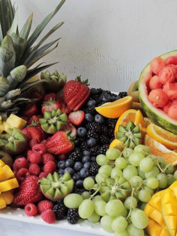 decorative fruit platter holding various summer fruits.