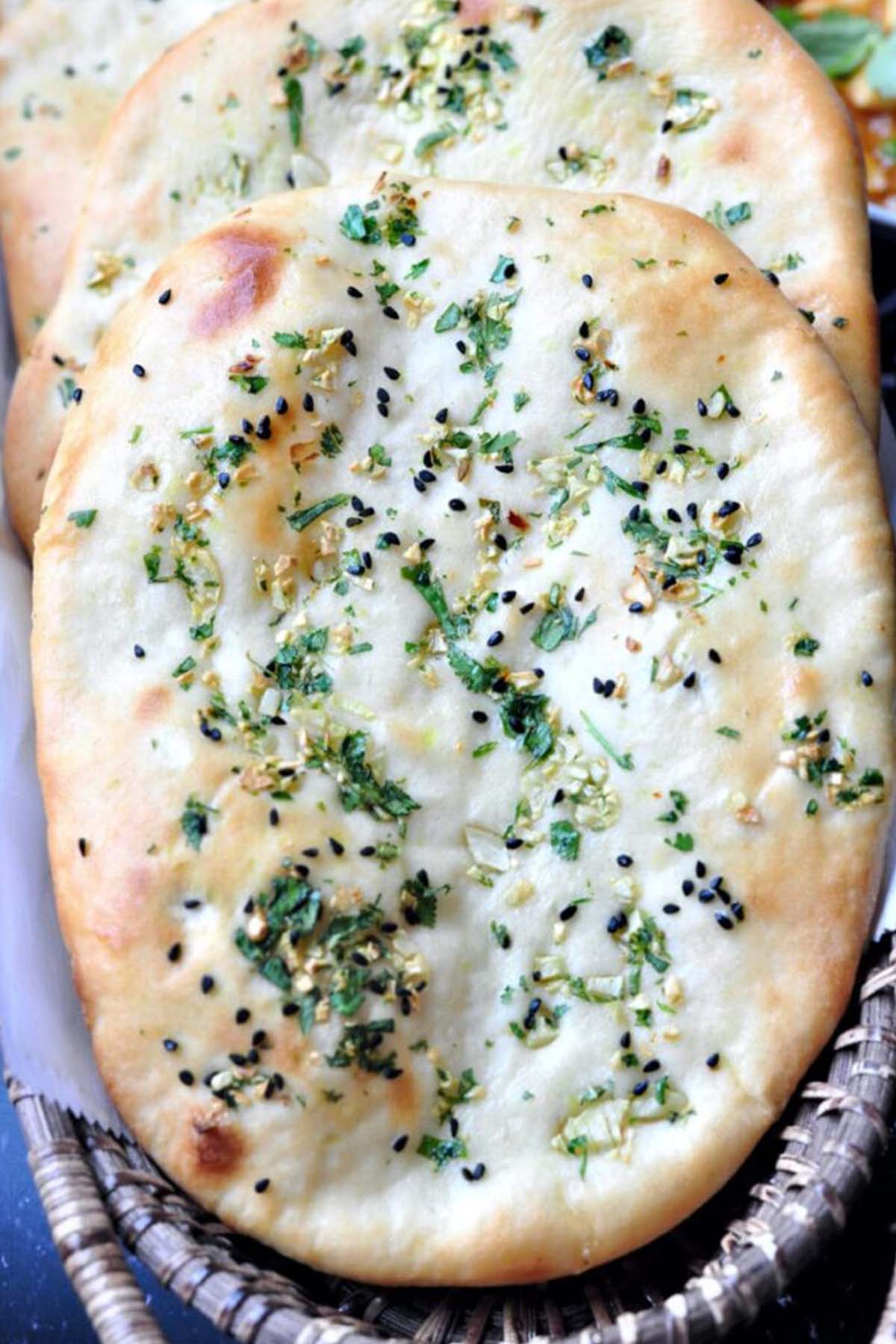 naan bread topped with parsley and sesame seeds.