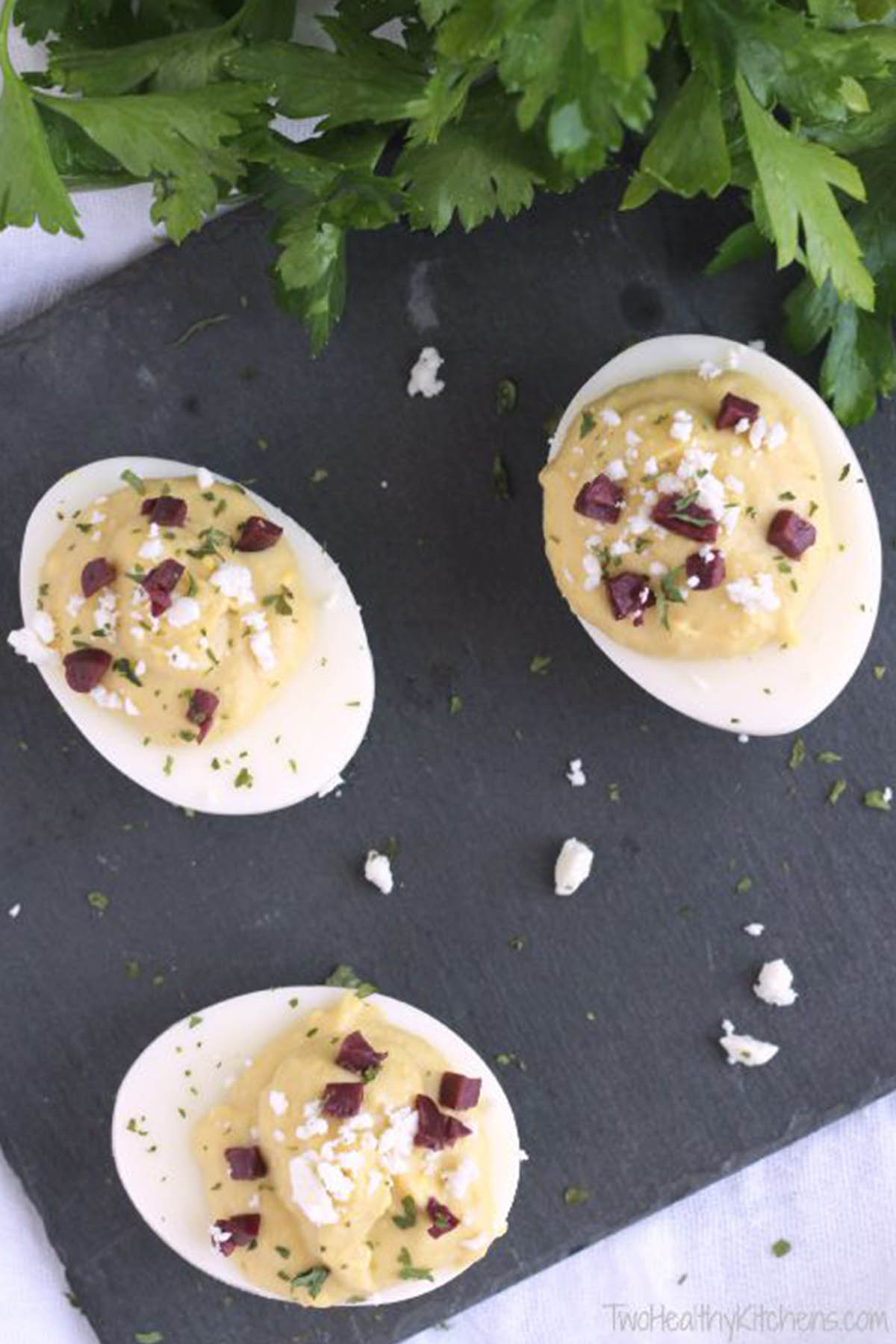 three deviled eggs garnished with feta cheese.