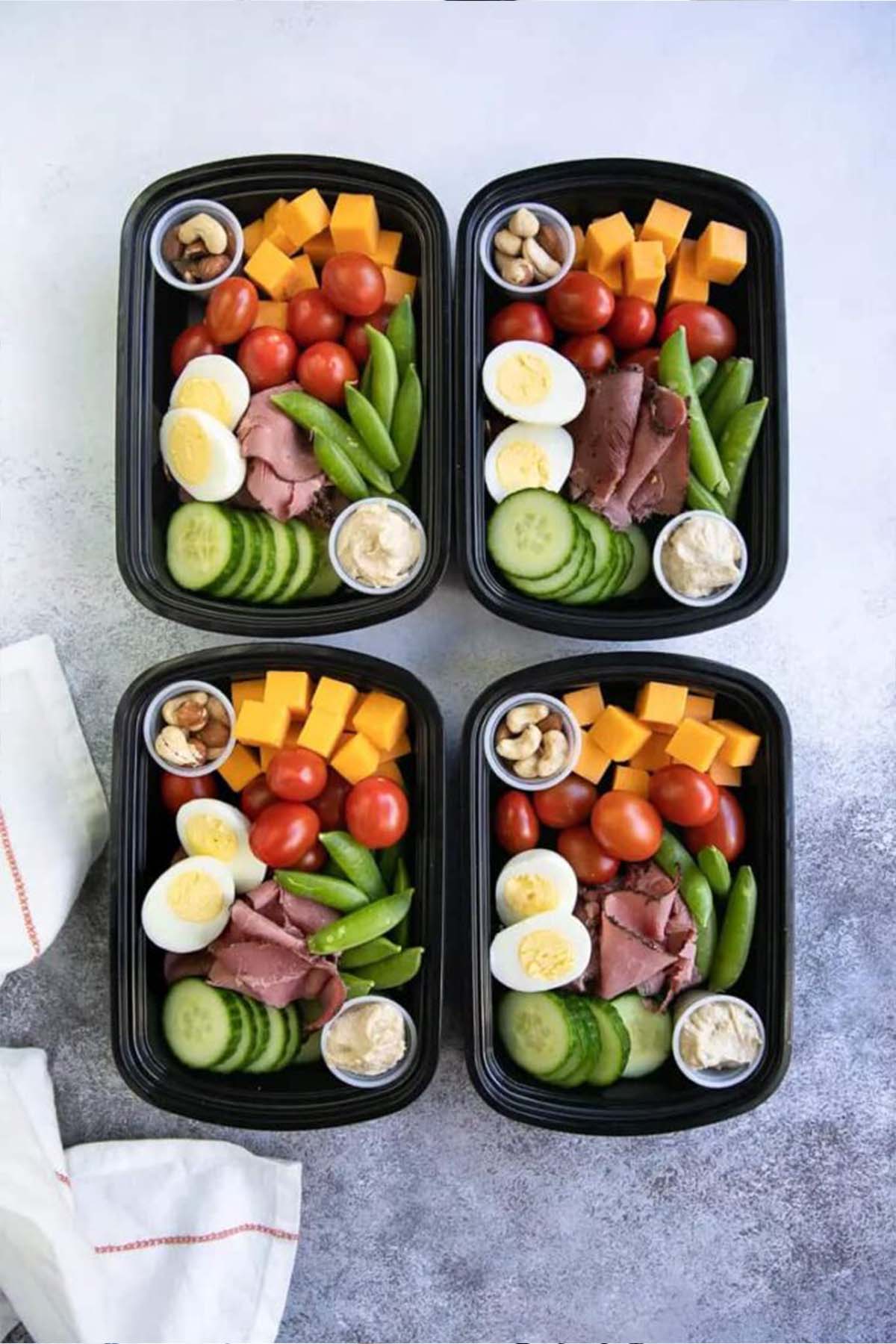 four containers with various healthy snacks.
