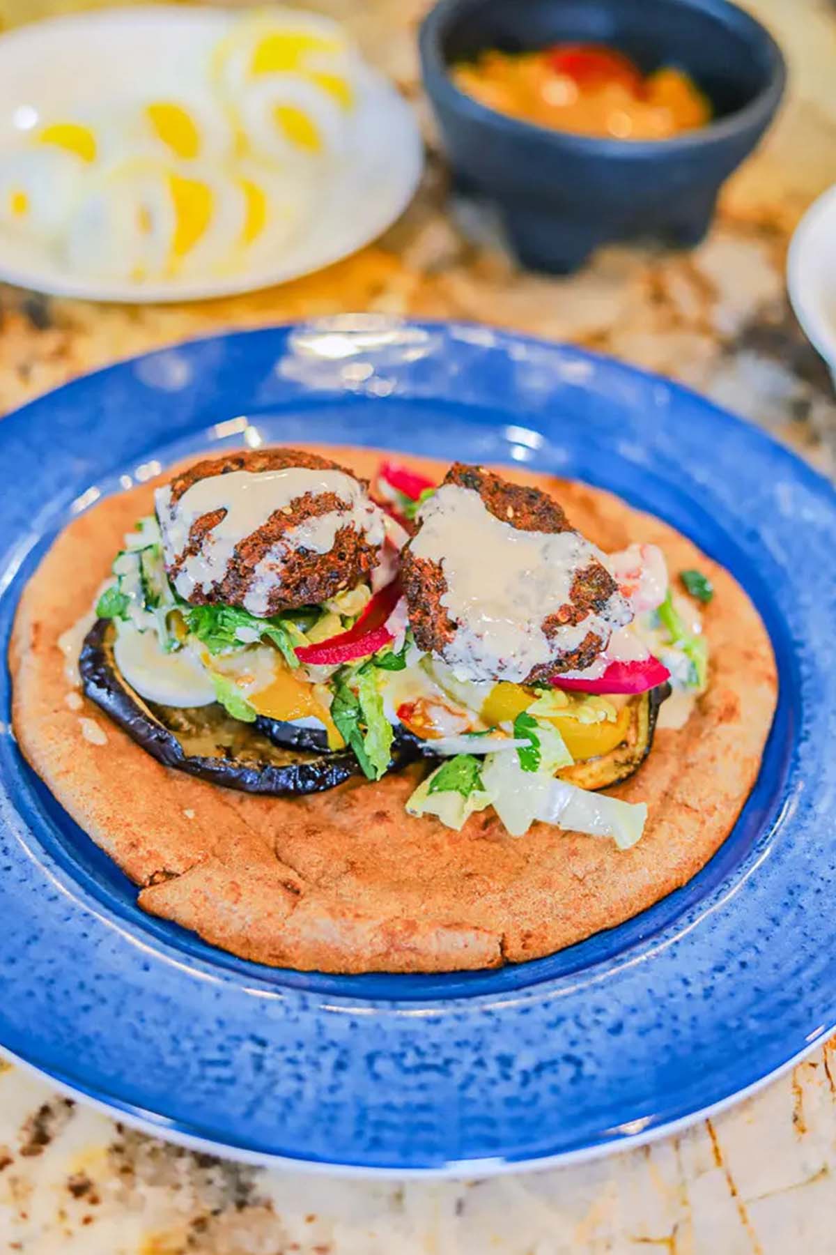 pita bread topped with roasted vegetables and falafel.