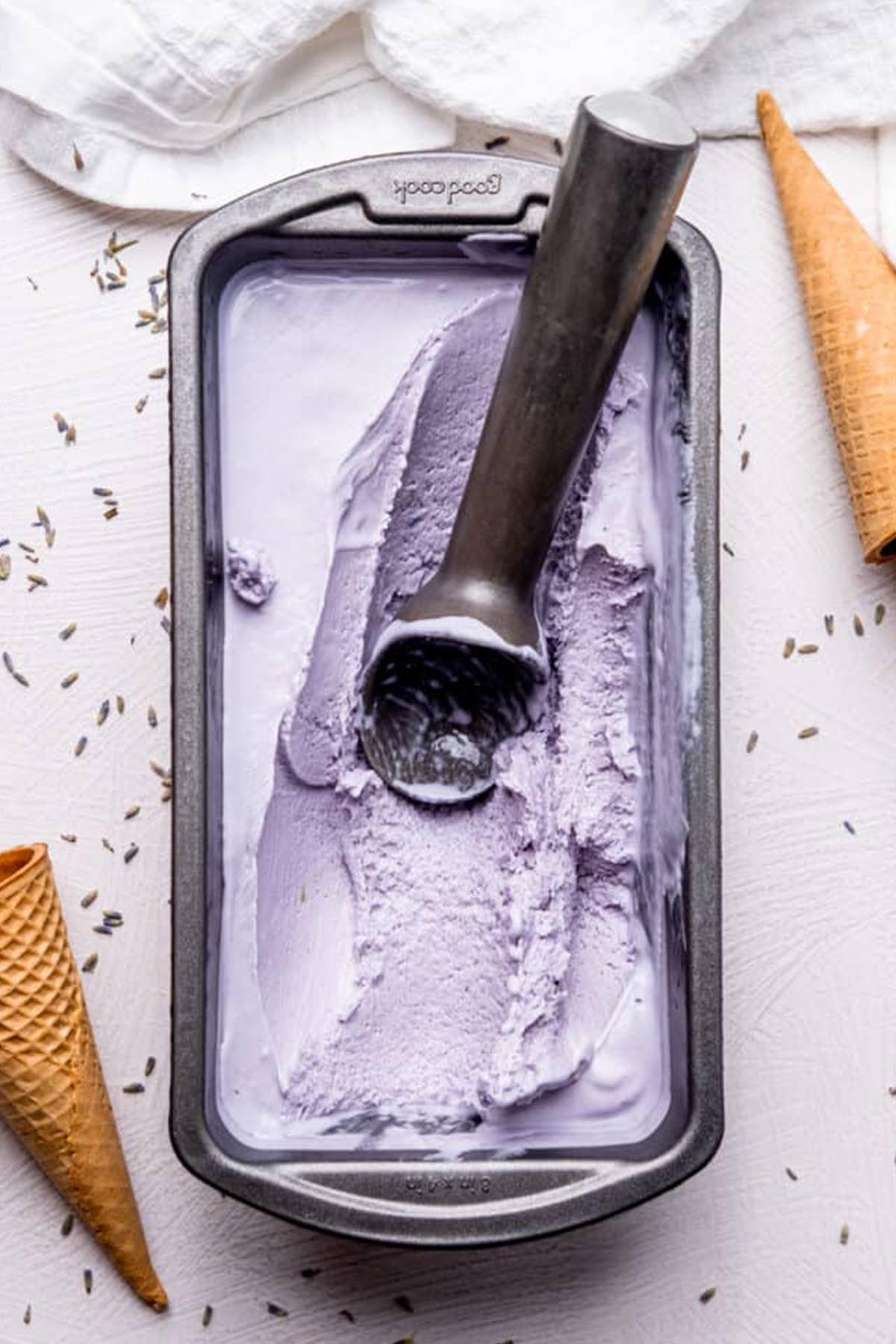 purple ice cream and ice cream scoop in a metal loaf pan.