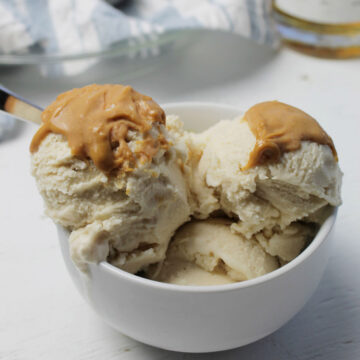 three scoops of ice cream topped with peanut butter in a bowl.