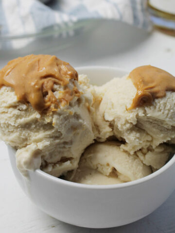 three scoops of ice cream topped with peanut butter in a bowl.