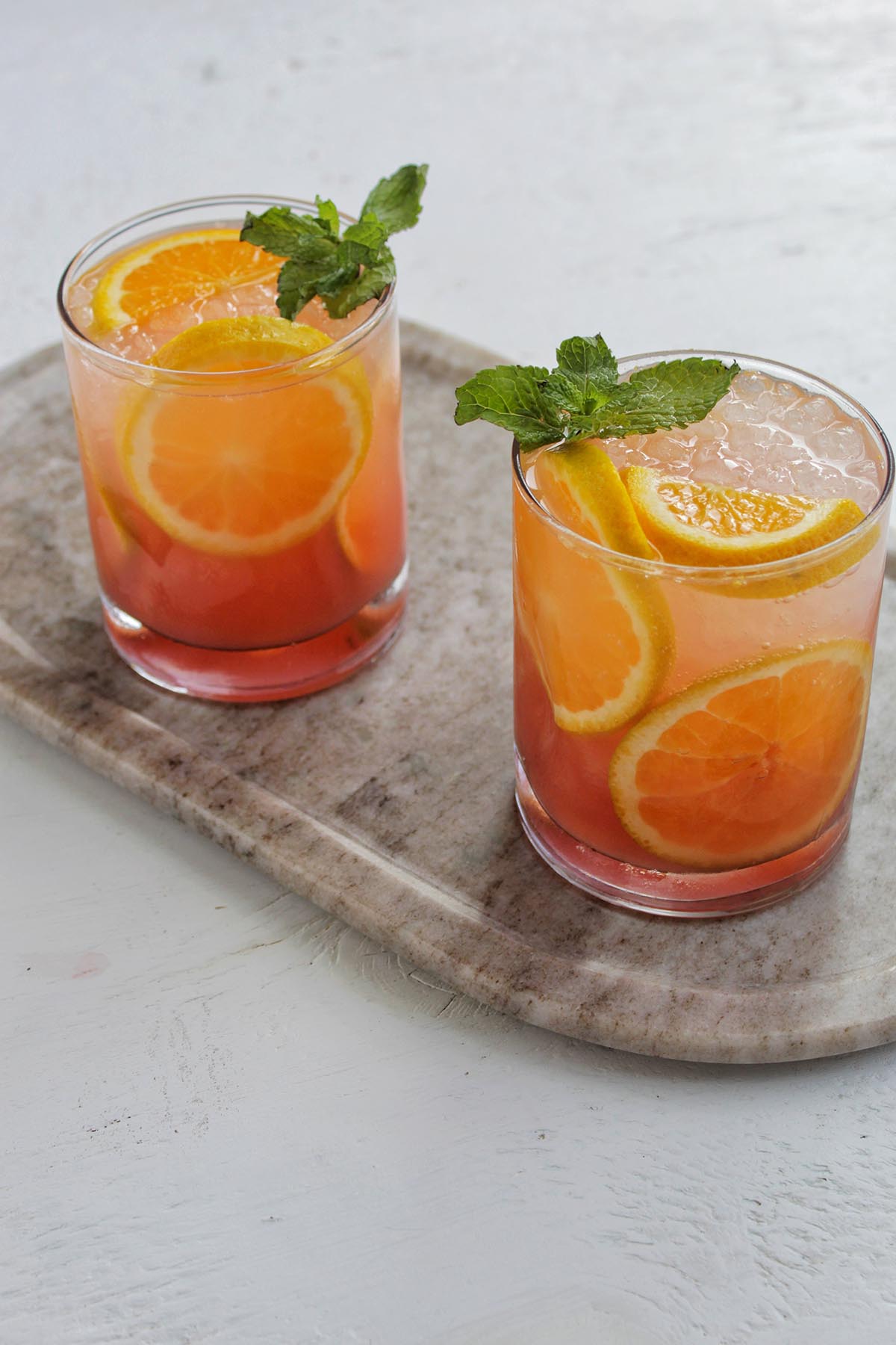 two lowball glasses filled with and orange flavored cocktail.