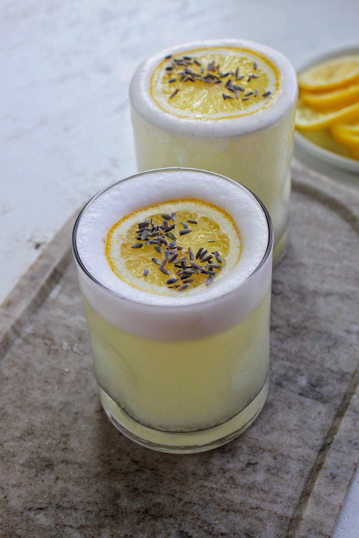 two lowball cocktail glasses filled with lemon pisco sour.