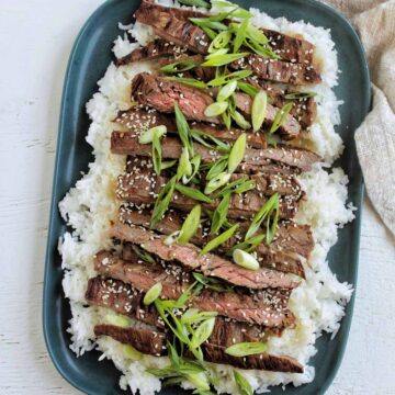 grilled skirt on a bed of rice topped with green onions.