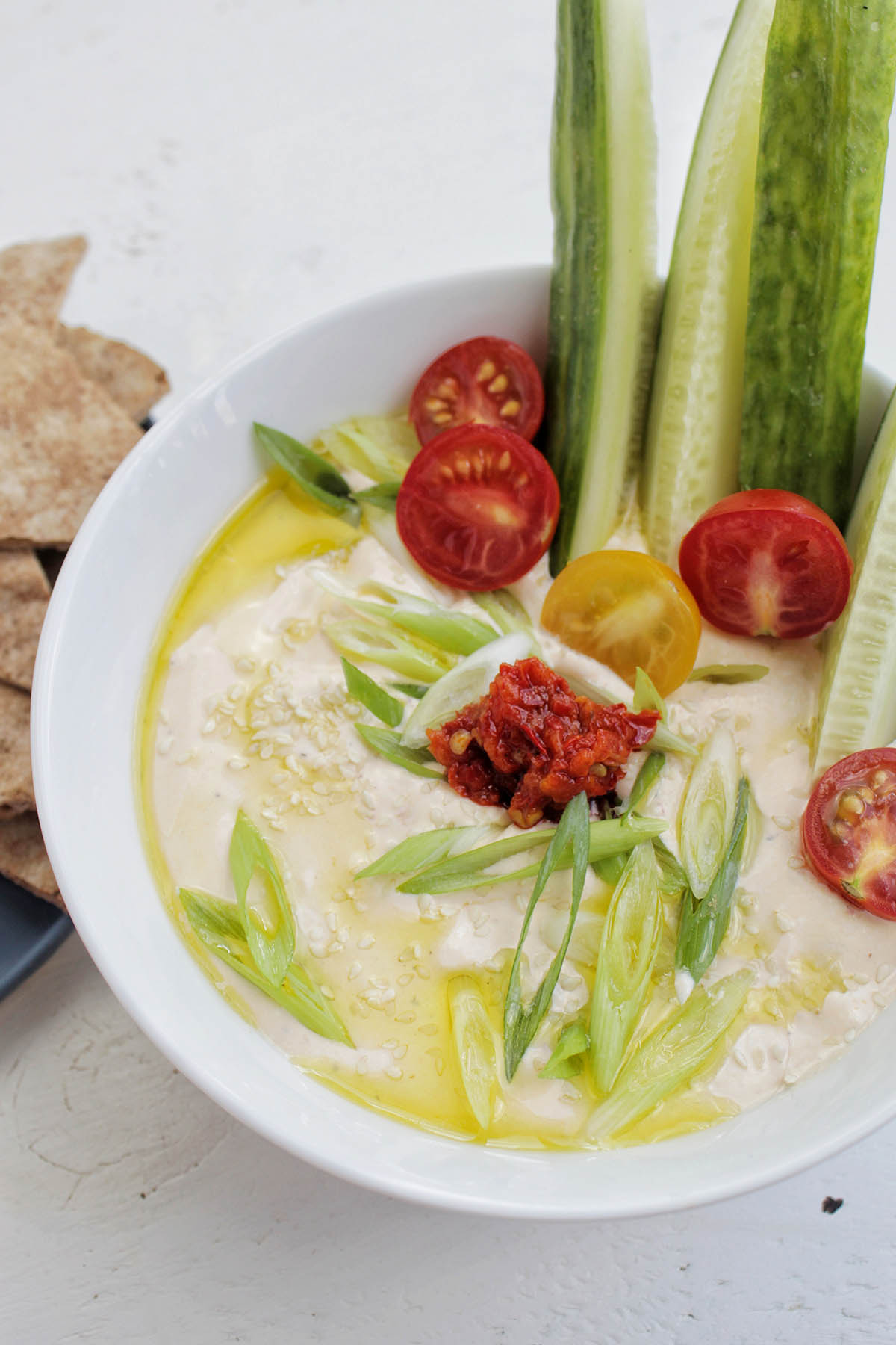 bowl of whipped feta dip garnished with green onions and sesame seeds.