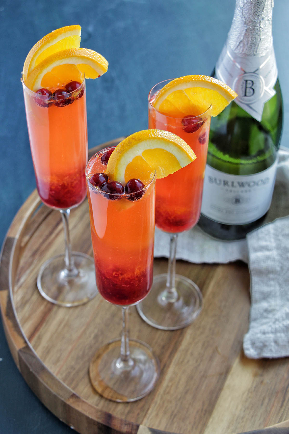 three champagne flutes on a serving tray next to a bottle of champagne.