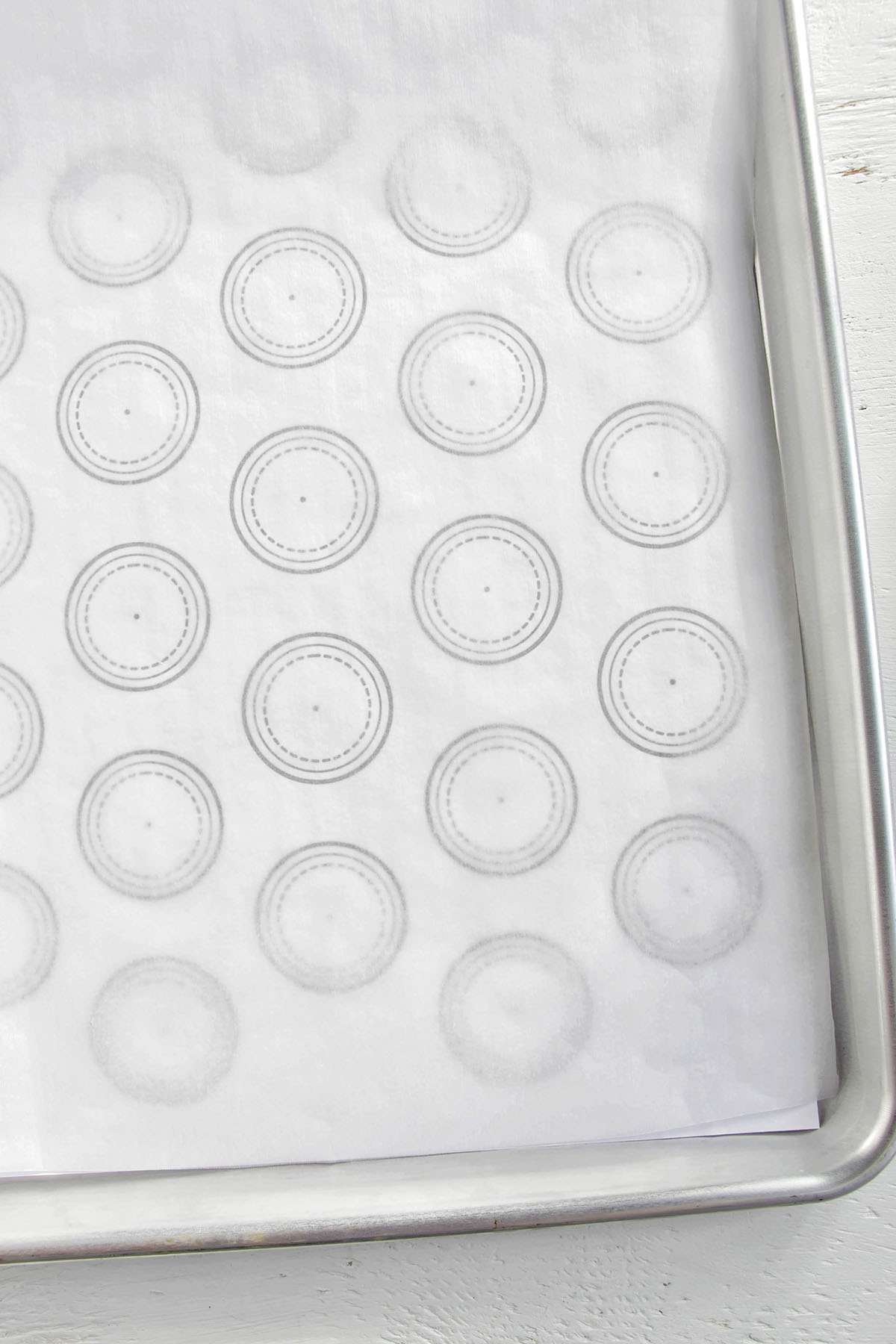 macaron piping guide under a parchment lined baking sheet.