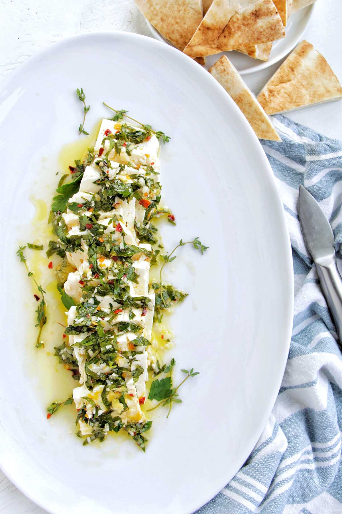 feta cheese squares garnished with herbs on a serving platter.