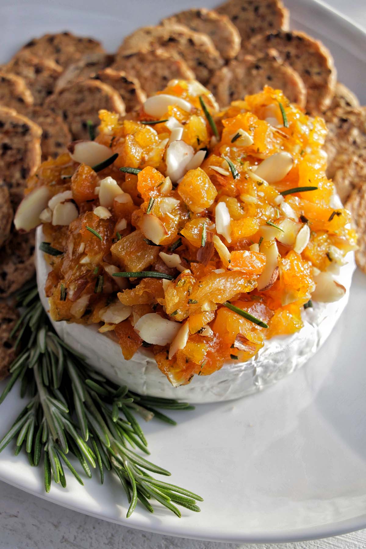 wheel of brie cheese topped with apricots and almonds.