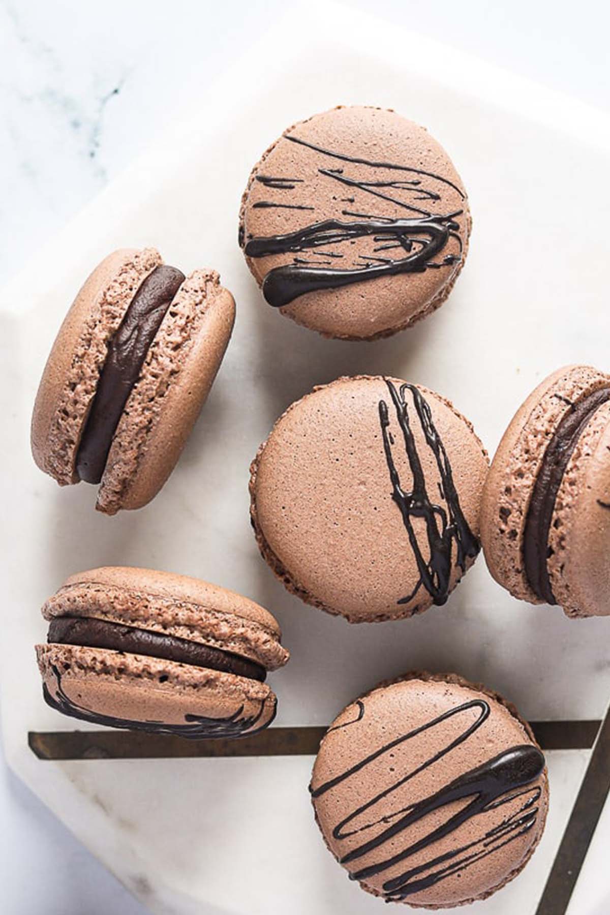 brown shelled macarons drizzled with dark chocolate.