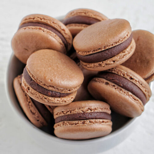 bowl filled with chocolate macarons filled with ganache.