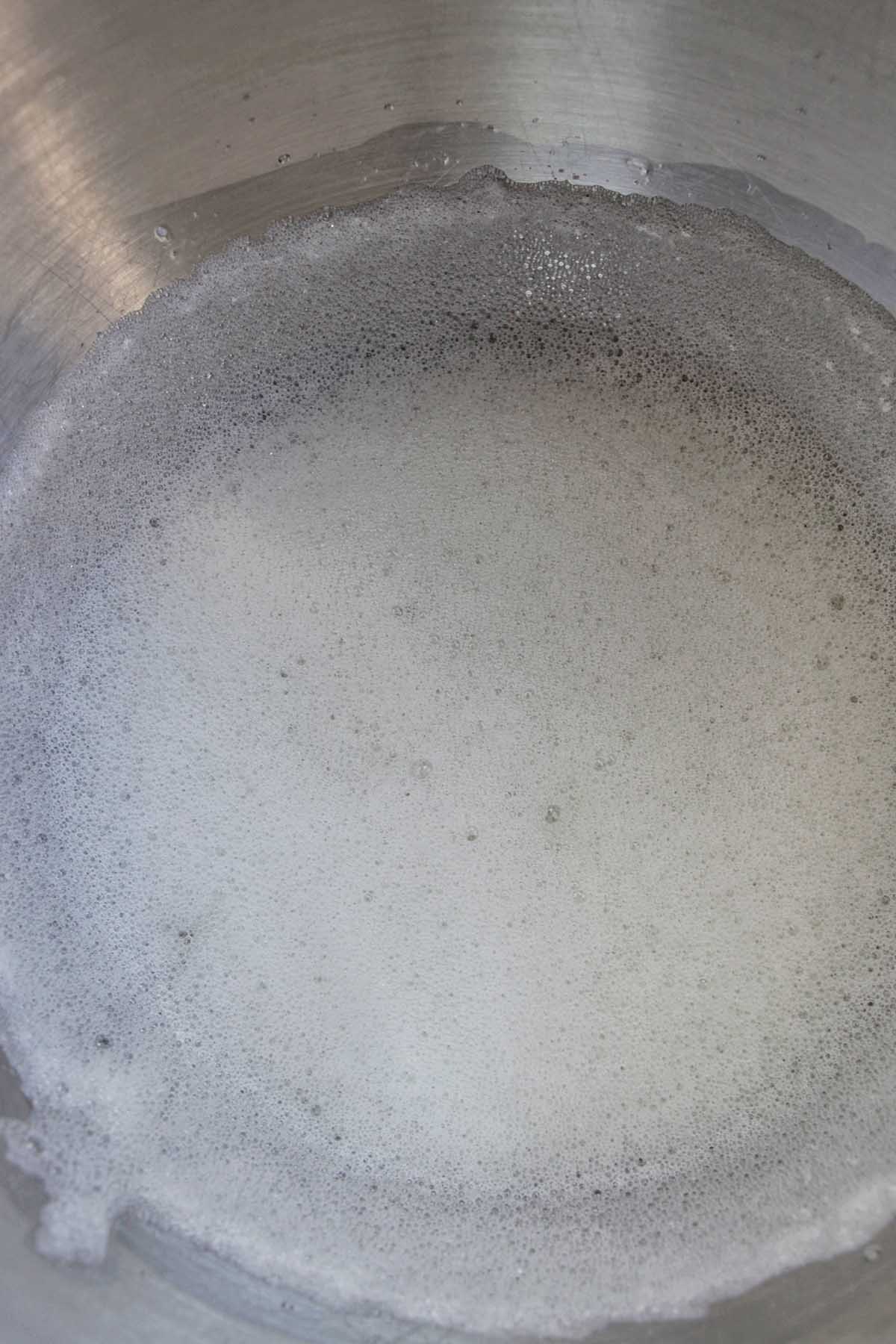 foamy egg whites in a metal mixing bowl.