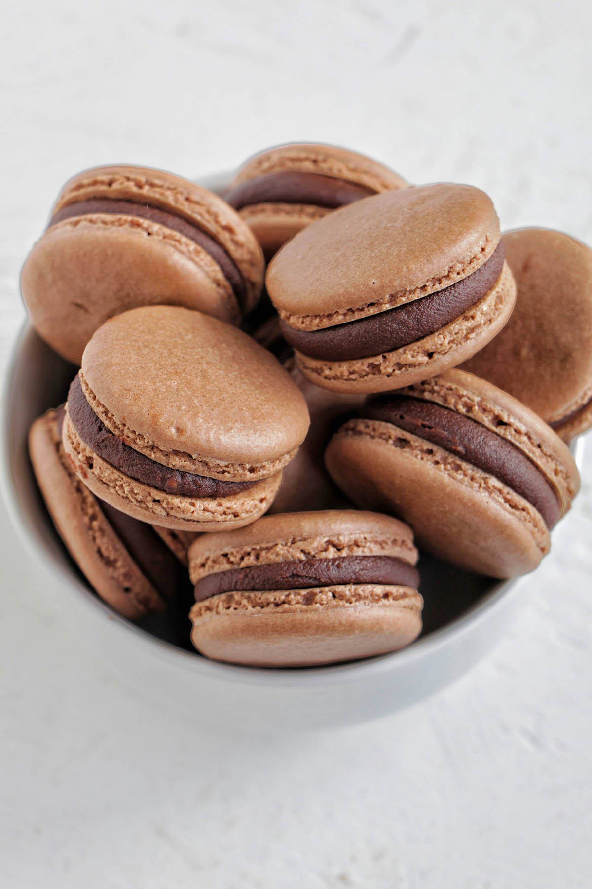 bowl filled with chocolate macarons filled with ganache.