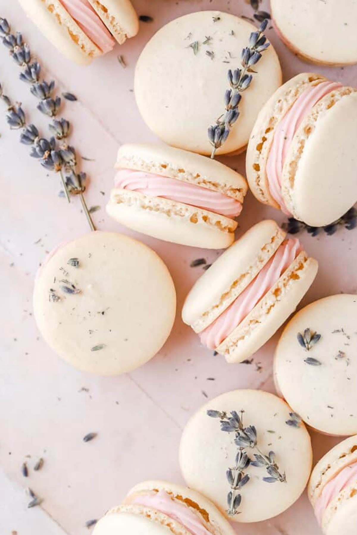 white shelled macarons with pink frosting filling.