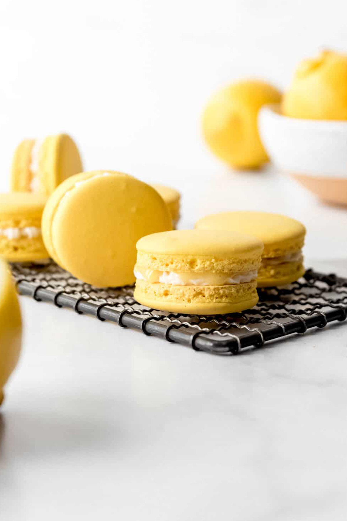 lemon macarons sitting on a wire cooling rack.