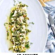 feta cheese topped with herbs on a white serving tray Pinterest pin.