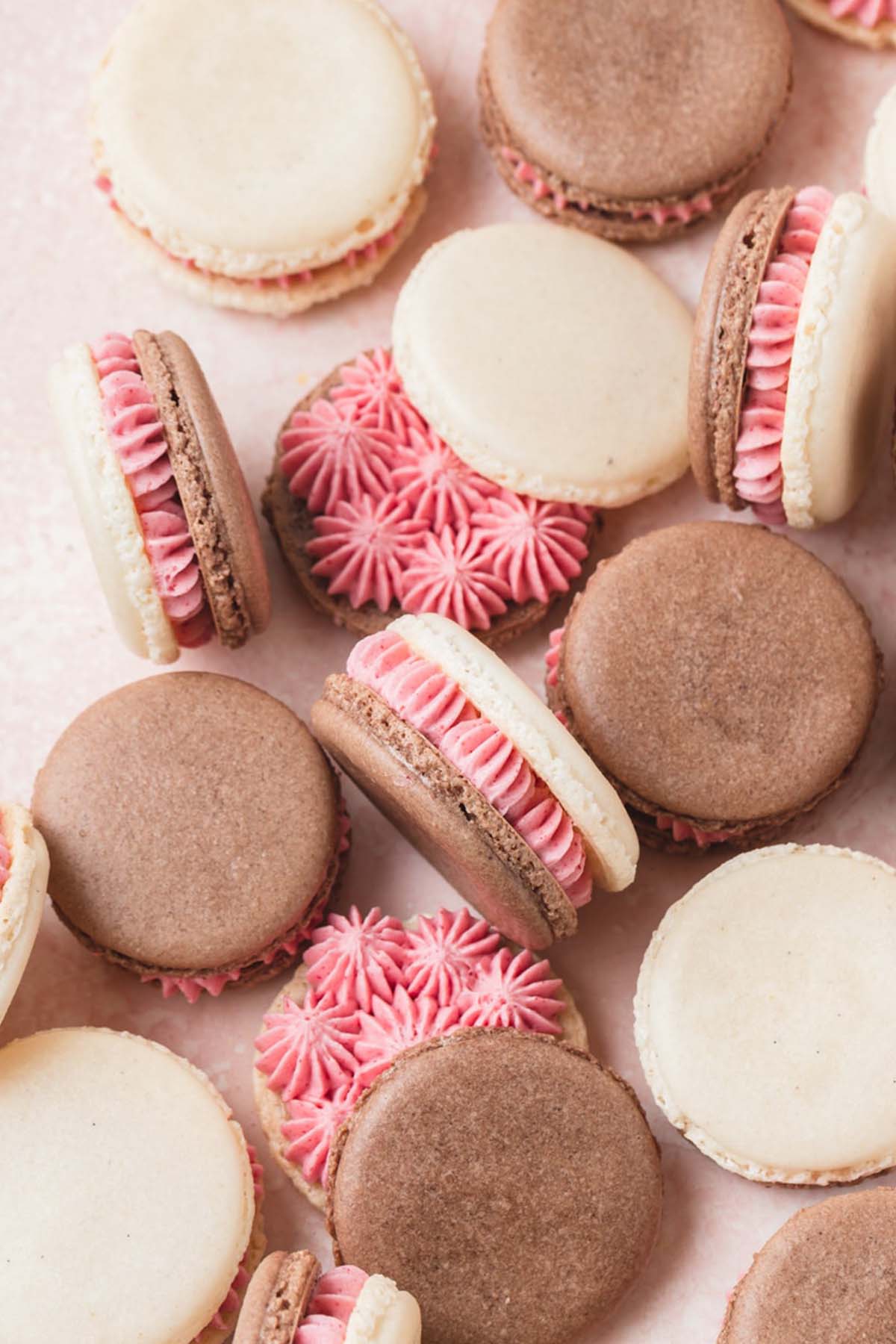 Neapolitan white and brown macaron shells with pink filling.