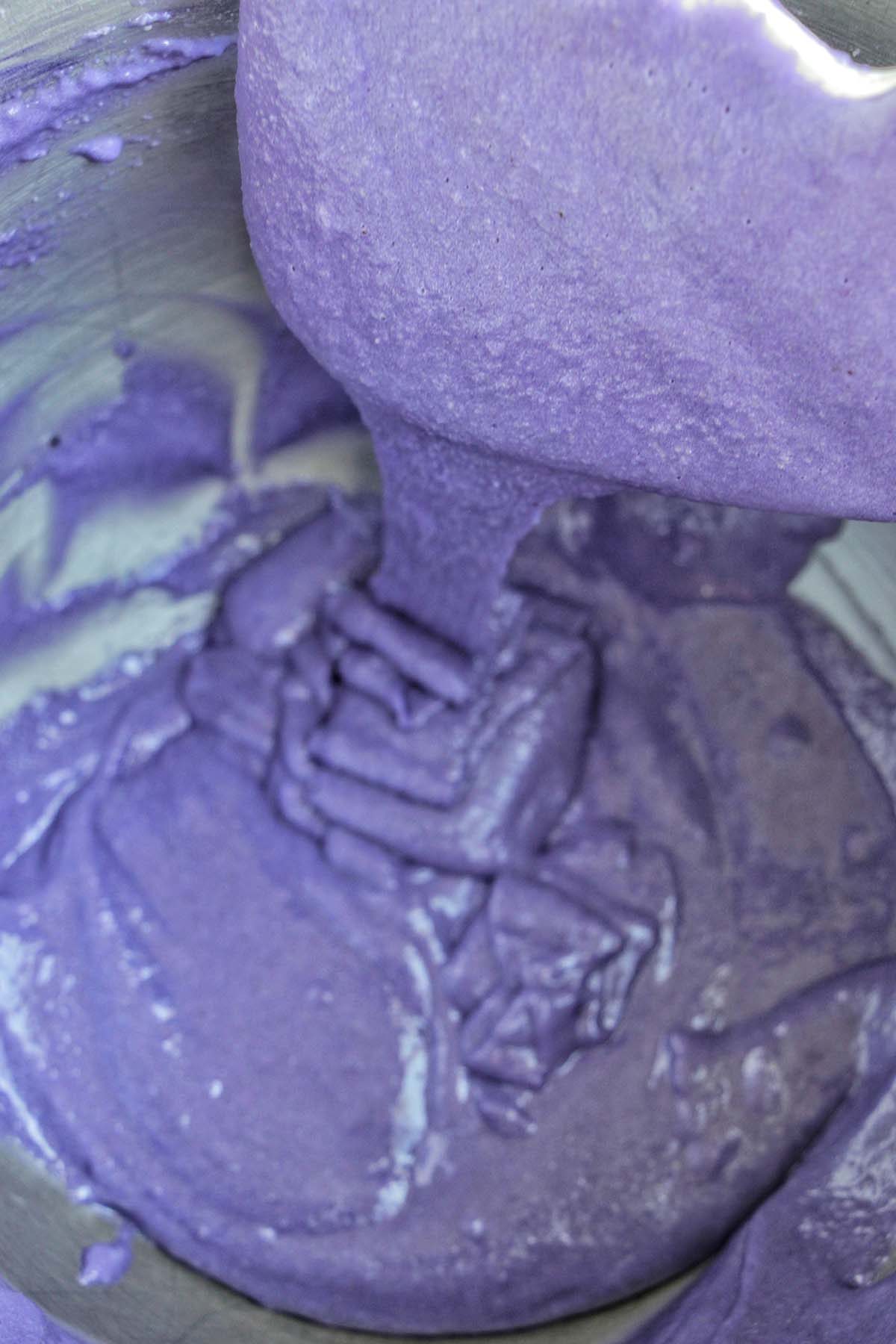 purple macaron batter dripping off a silicone spatula.