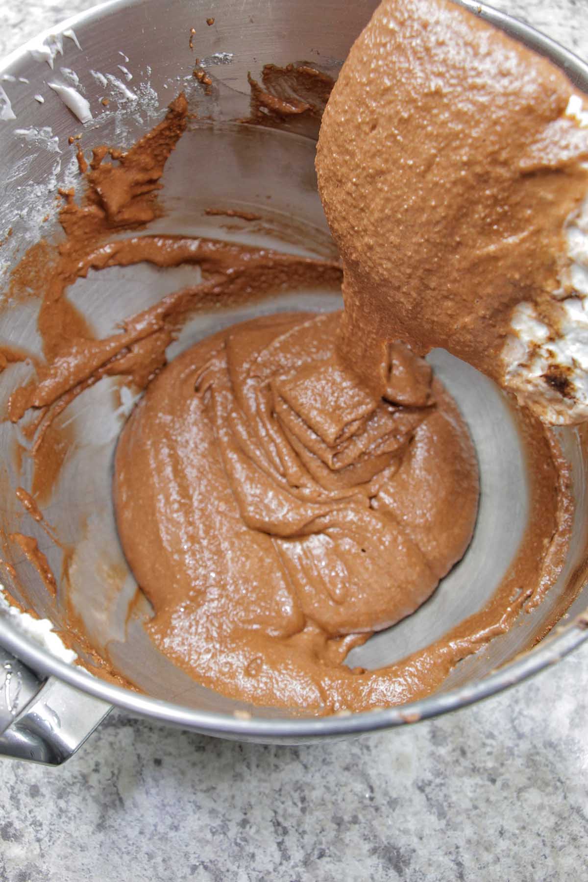 brown macaron batter flowing off silicone spatula.