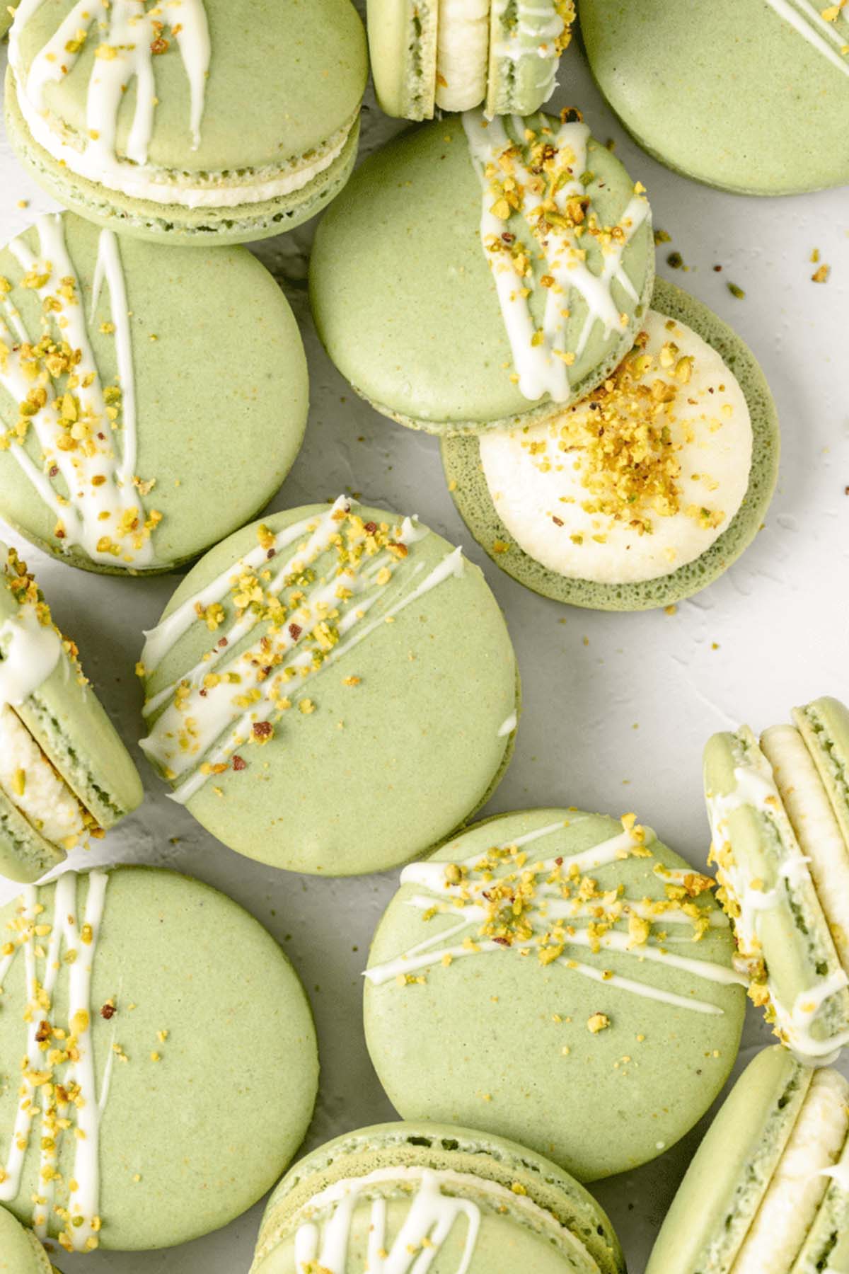 green macaron shells drizzled with white chocolate and chopped pistachios.