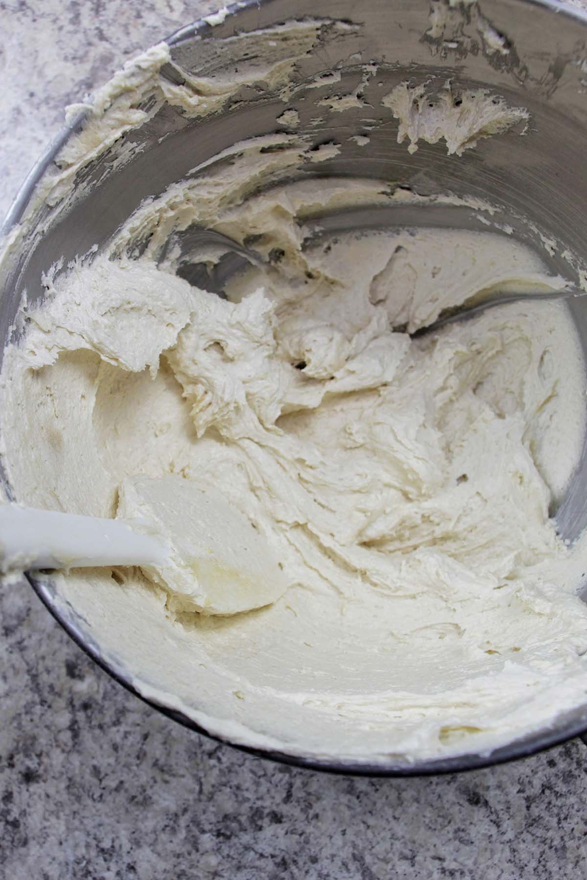 pushing cookie dough buttercream onto the side of a mixing bowl.
