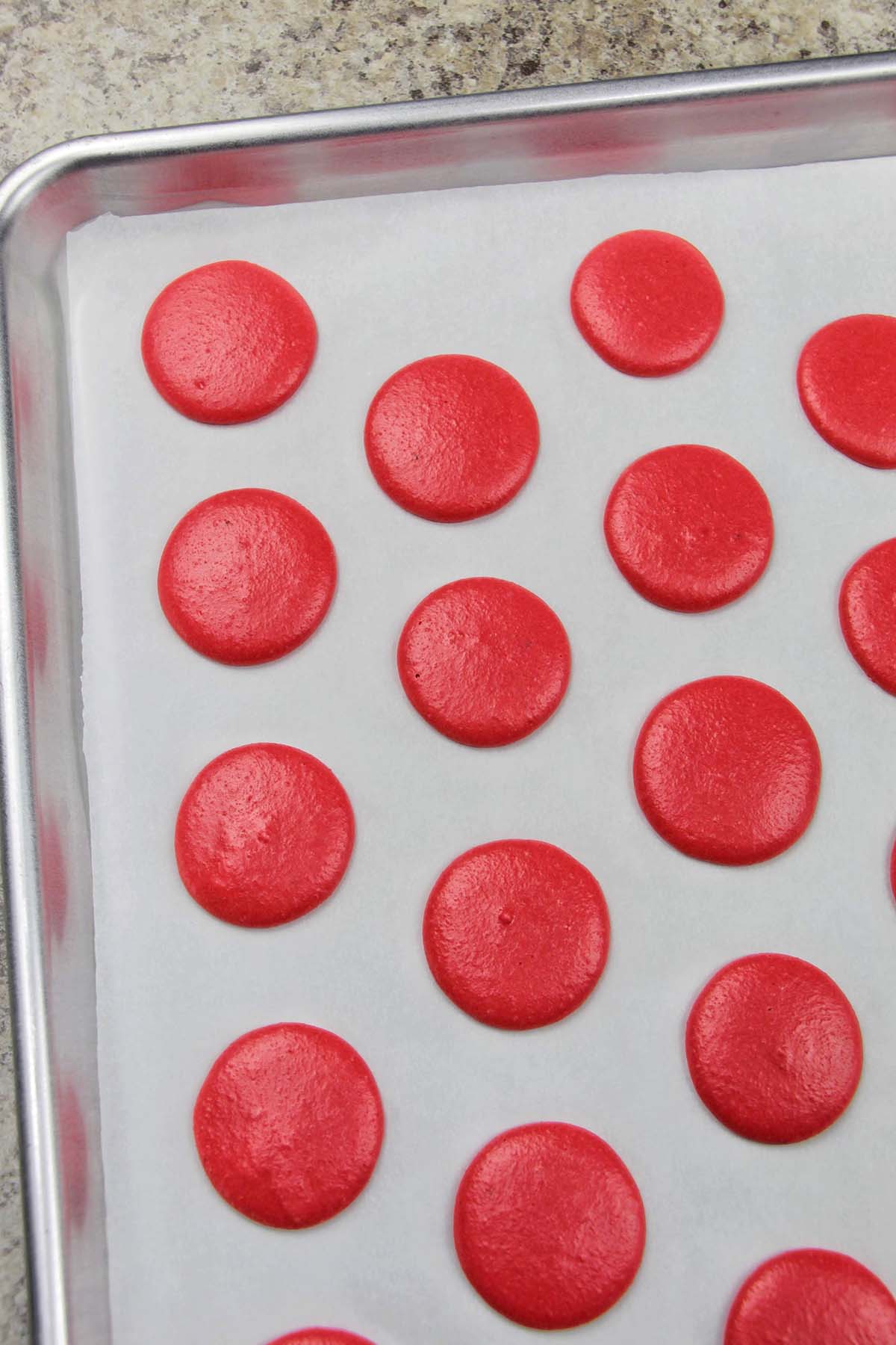 dried red macarons on a parchment lined baking sheet.