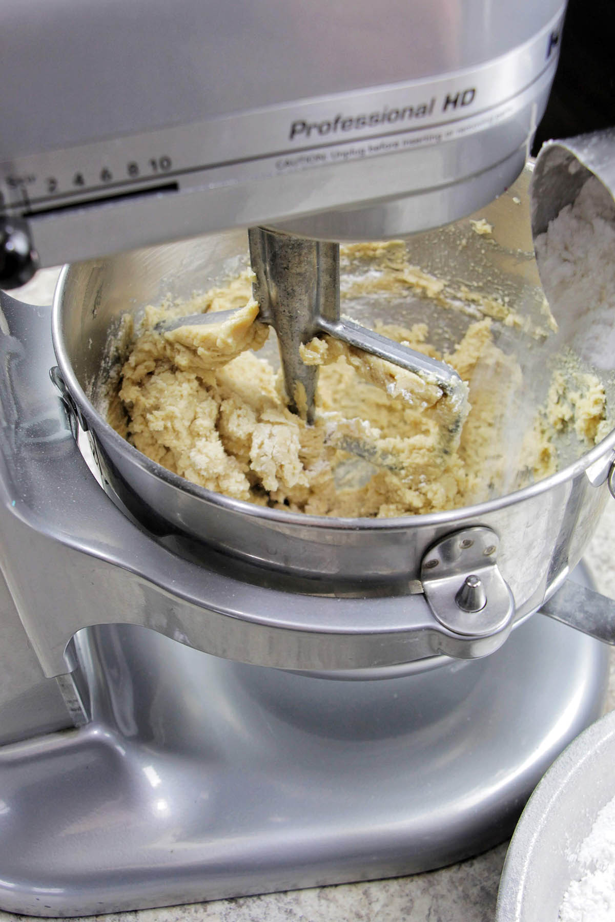 pouring confectioners' sugar into a KitchenAid stand mixer.