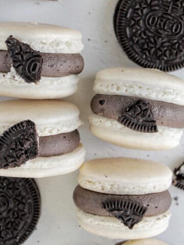white macaron shells filled with black Oreo buttercream topped with an Oreo cookie piece.