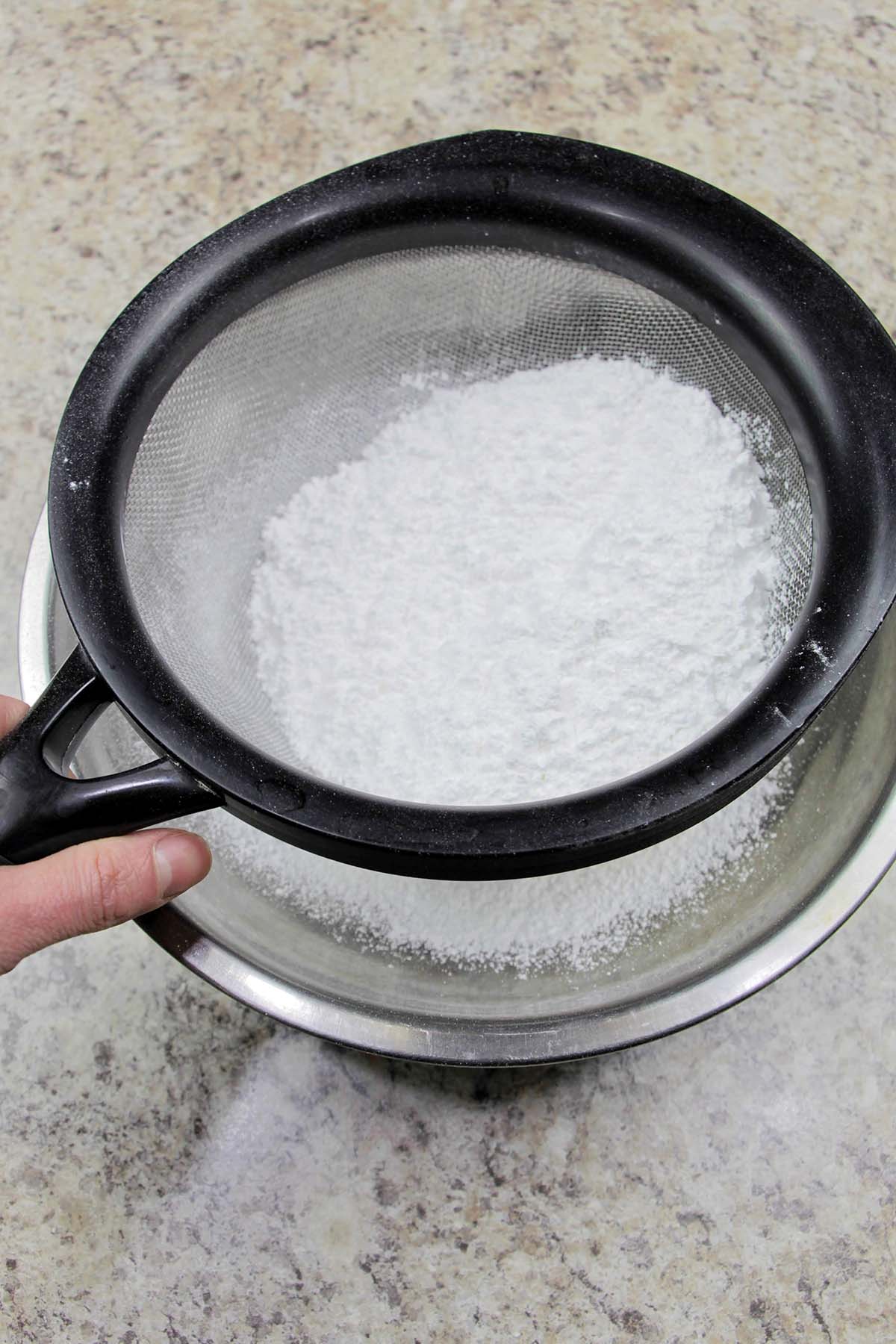 sifting confectioners' sugar and flour into a mixing bowl.